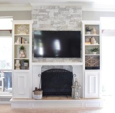 a living room with a large television mounted on the wall above a fireplace and built in bookshelves