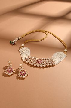 Embrace sophistication with this Kundan choker set, featuring delicate pearl lines and a charming pink floral center. Complete with exquisite dangler earrings, this set exudes elegance and is crafted with meticulous detail in mixed metal and 22kt gold plating. Finish: 22KT Gold Plating Material: Brass, Kundan,Pearls Color: Gold, White Size: Free Size, Adjustable Closure Type: Draw String Box Contains: 1 Necklace, 1 Pair Earrings Elegant Pink Kundan Necklace For Formal Occasions, Elegant Pink Kundan Necklace For Formal Events, Traditional Pink Kundan Necklace For Formal Occasions, Elegant Pink Kundan Necklace, Elegant Pink Meenakari Jewelry Sets, Elegant Pink Jewelry Sets For Diwali, Elegant Pink Meenakari Choker, Elegant Pink Meenakari Necklace, Elegant Pink Pearl Necklace For Festivals