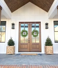 an instagram page with two wooden doors and potted plants on the front porch