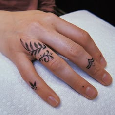 a woman's hand with two small tattoos on her left and the other half of her finger