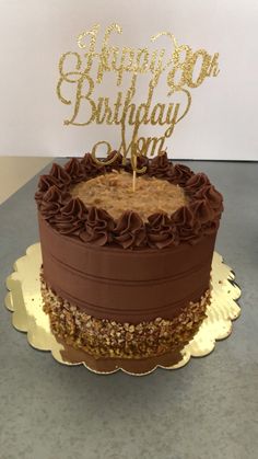 a chocolate birthday cake with the words happy 90th birthday on it and a candle in the shape of a heart