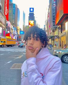 a man with curly hair and piercings standing on the street in new york city