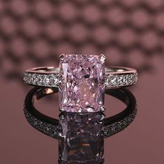 a fancy ring with a pink diamond surrounded by white and black diamonds on a purple background