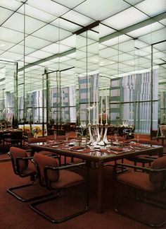 an empty dining room with chairs and tables in front of large mirrors on the wall