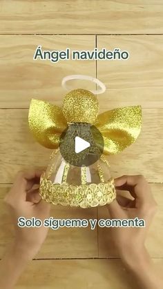 someone is holding up a gold bell with a bow on it and the words angel naviddeno written in spanish