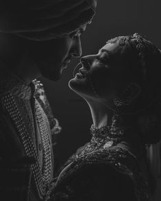 two people in black and white with one woman kissing the other's foreheads