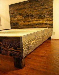 a bed made out of wood sitting on top of a hard wood floor next to a wall