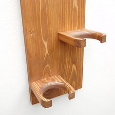 a wooden wall mounted toothbrush holder on the side of a white wall with woodgrain