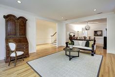 a living room with hardwood floors and white furniture on top of a hard wood floor