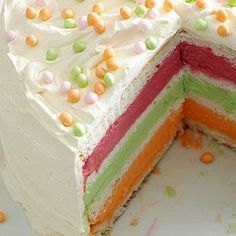 a multi - colored cake with white frosting and sprinkles