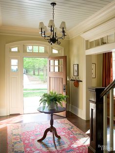 an entry way with a table and potted plant on the rug in front of it