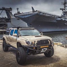 an off - road truck parked in front of a large ship