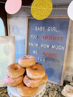 there are donuts stacked on top of each other in front of a sign that says baby girl you donut know how much we love you