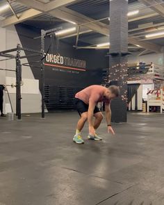 a man is squatting down on the floor in an indoor crossfit gym