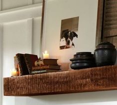 a shelf with candles, books and pictures on it