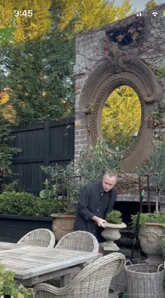 a man standing in front of a table surrounded by potted plants