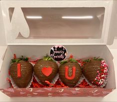 three chocolate covered strawberries in a box with the word u on it and hearts