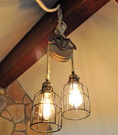 two light fixtures hanging from the ceiling in a room with stone walls and wood beams