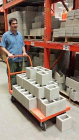 a man is pushing a dolly with cement blocks on it in a storage area at a warehouse