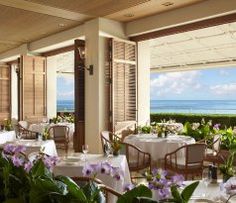 an outdoor restaurant with tables and chairs overlooking the ocean