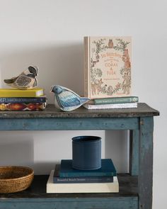 a blue table with books and a bird figurine on top