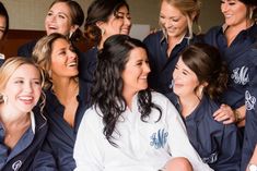 a group of women sitting next to each other in front of a mirror and smiling