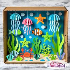 an open cardboard box with cutouts of sea animals and fish on the bottom, hanging from strings