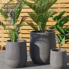 three planters sitting on top of a wooden deck