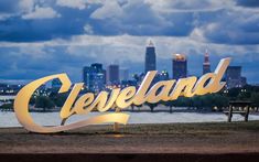 a large metal sign that says cleveland in front of a cityscape