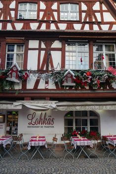 the outside of a restaurant with tables and chairs in front of it, decorated for christmas