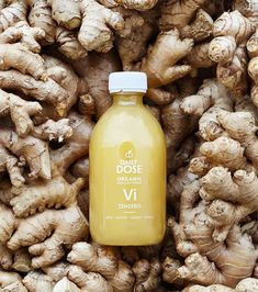 a bottle of orange juice sitting on top of a pile of ginger root roots with the words organic vii in front of it