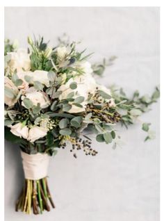 a bouquet of white flowers and greenery on a wall