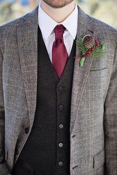 a man wearing a suit and tie with a red flower in his lapel pocket