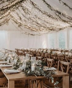 tables with candles and greenery are set up in a tent for a wedding reception