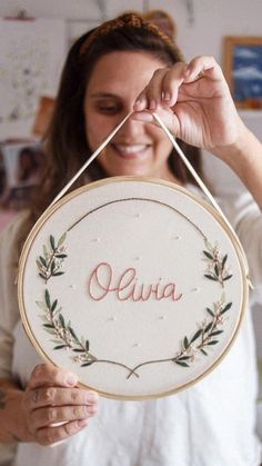 a woman is holding up a personalized embroidery hoop with the word ava on it