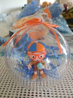 a glass ornament with an orange and blue hat on it sitting on a table