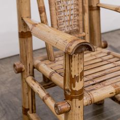 a chair made out of bamboo and wicker with no back support, sitting on a wooden floor