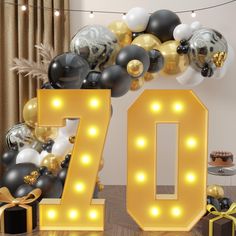 the number seventy is surrounded by balloons and streamers in black, gold and white