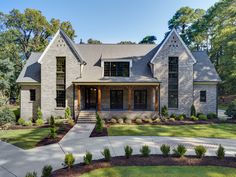 a large brick house with lots of windows and landscaping in front of the home is surrounded by trees