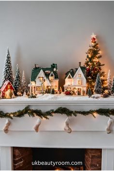 a fireplace mantel decorated with christmas trees and miniature houses on it's mantle