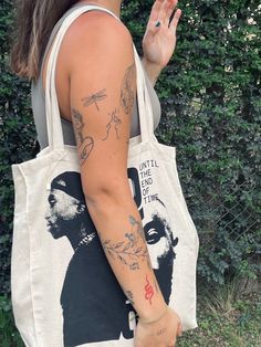 a woman with tattoos on her arm holding a tote bag