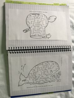 two notebooks with drawings on them sitting on top of a sheet of white paper