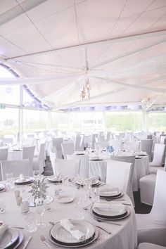 the tables are set for an event with white linens and place settings on them