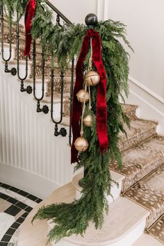 christmas decorations on the banisters and stairs at the bottom of the staircase are adorned with greenery