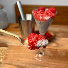 a spoon full of raspberry chia pudding on top of a wooden table