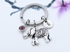 an elephant keychain with two charms attached to it's side and a flower in the background