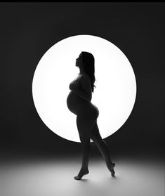 a pregnant woman walking in front of a round light