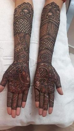 two hands with henna tattoos on them, one is showing off the intricate design