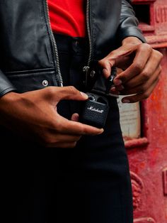 a man holding a camera in his hand while standing next to a red wall with an open door