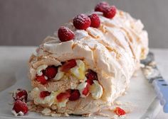 a pastry on a plate with raspberries and cream frosting next to a fork